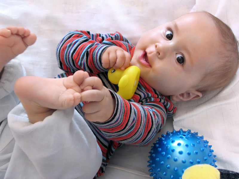 Happy baby looking at the camera while playing with his toes